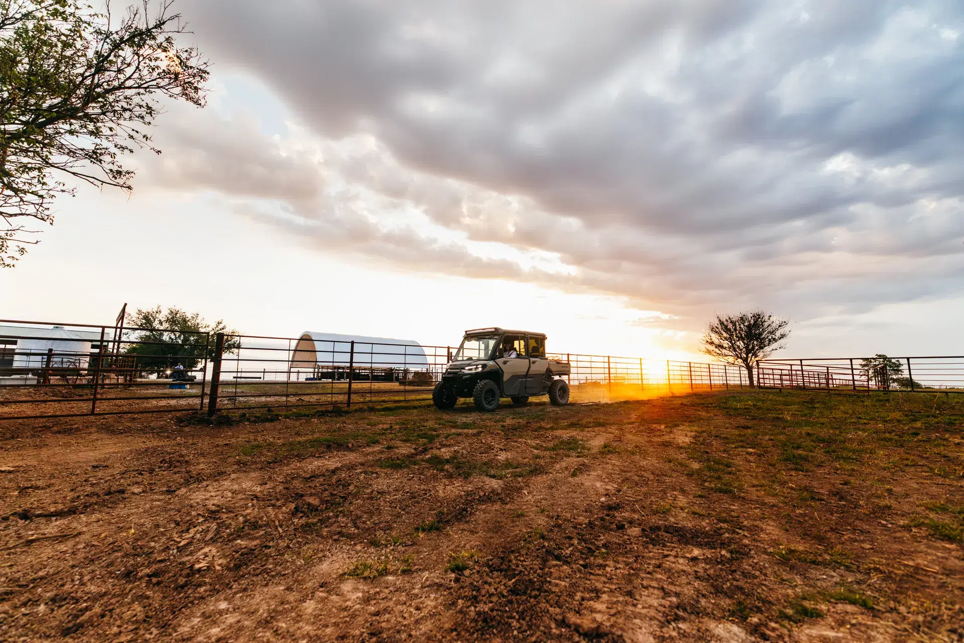 Côte-à-côte Can-Am Defender MAX 2027 traversant une ferme au coucher du soleil